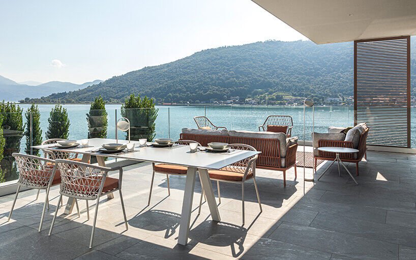 Pedrali Panarea outdoor lounge chairs in light gray polypropylene with perforated oval backrest, arranged on white tables on a terrace with cliff and sea views 