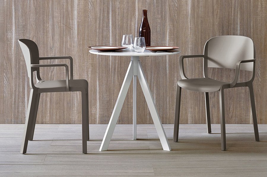 Two Pedrali Dome indoor and outdoor chairs in dove gray polypropylene, placed in front of a round white table. 