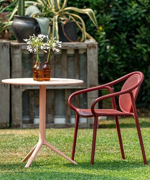 Red Remind chair by Pedrali and pink Elliot Pedrali table in the garden of a restaurant.