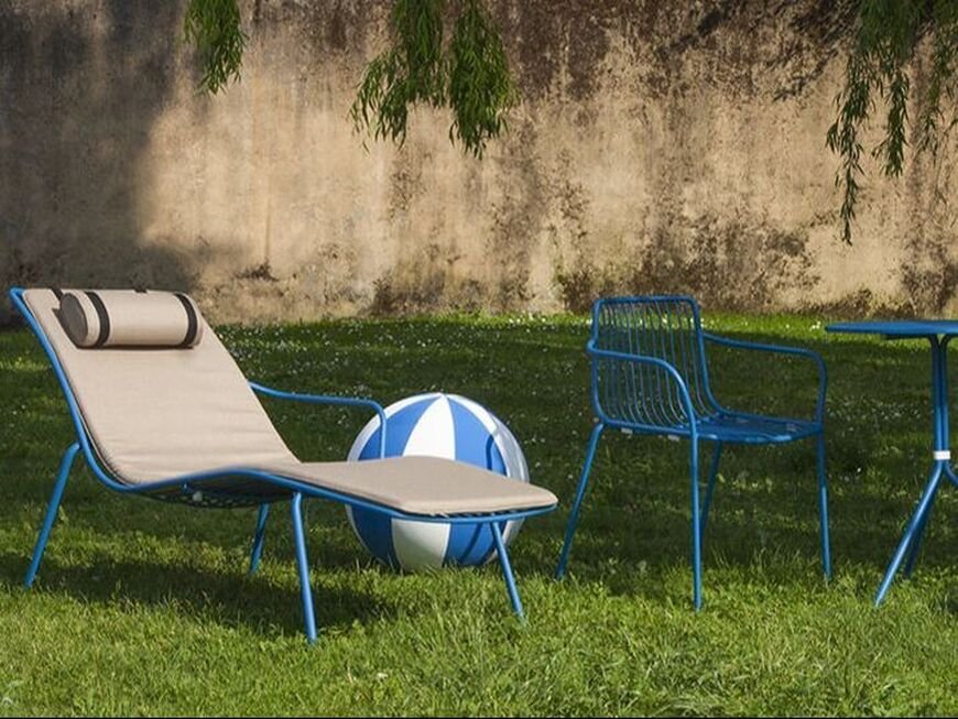 Nolita Pedrali blue sunbed next to the lawn, in an outdoor space of a hotel.